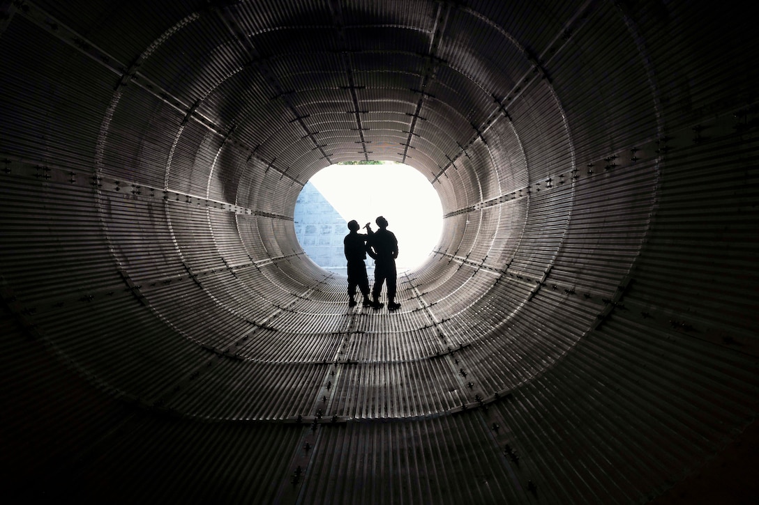 Airmen inspect an exhaust tube.