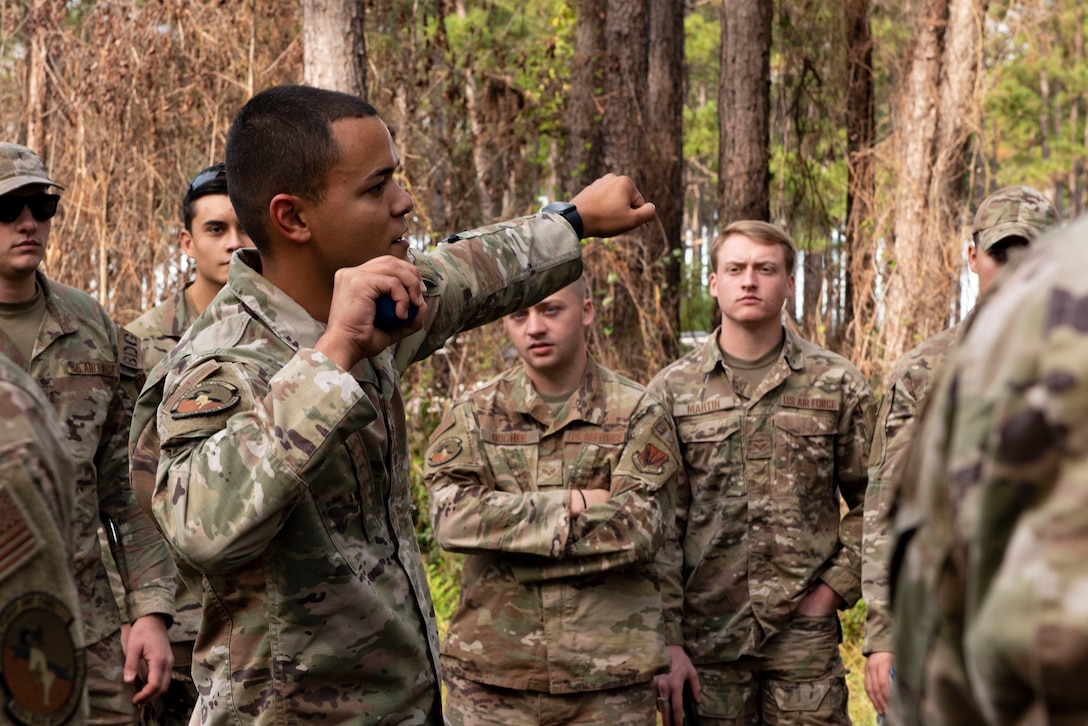 A photo of an Airman instructing other Airmen on how to throw a grenade.