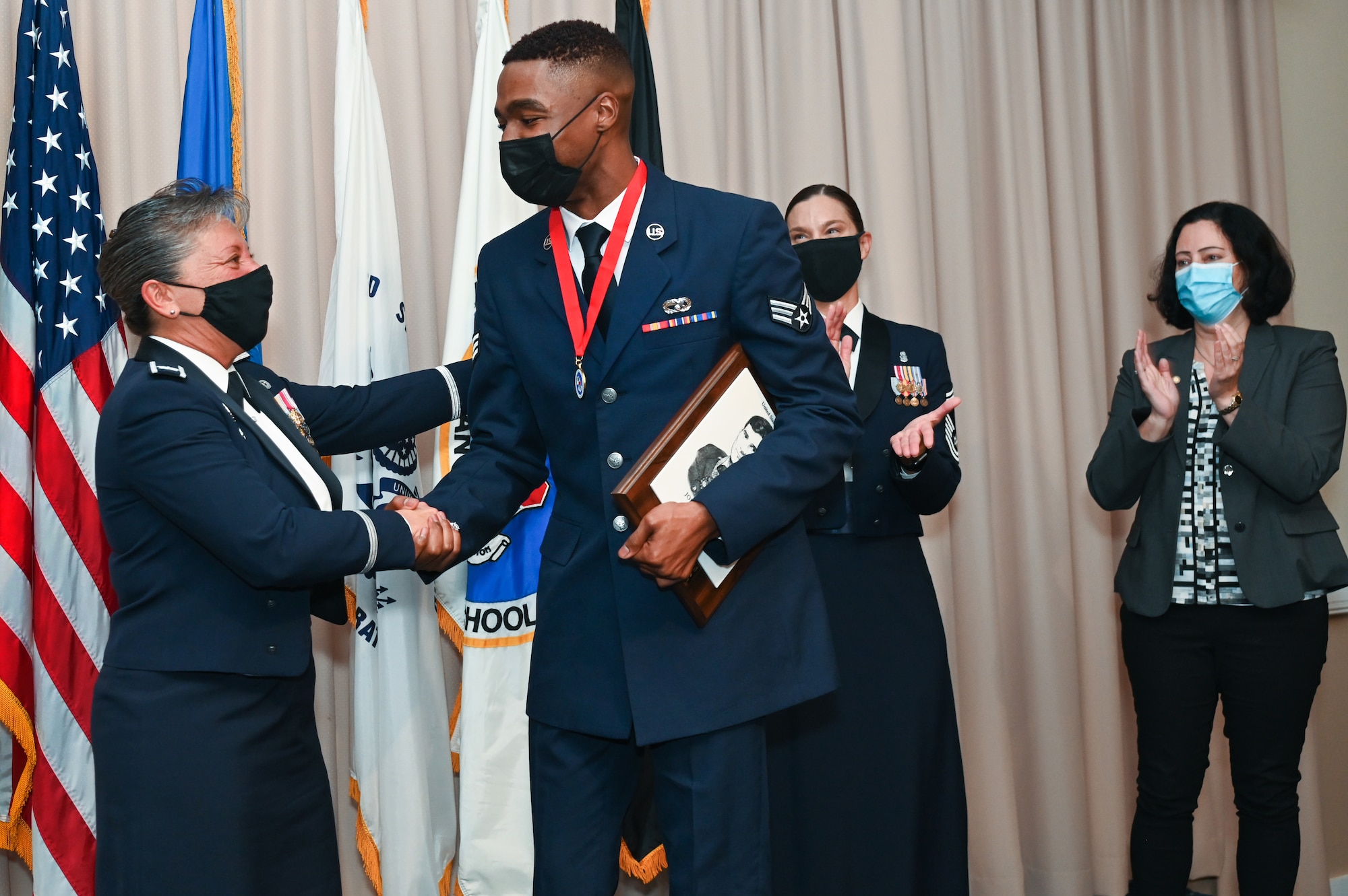 installation commander, shakes hands with Airman