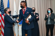 Col. Katrina Stephens, left, installation commander, shakes hands with Senior Airman Jachin Henderson, Joint Personal Property Shipping Office Northeast shipment distribution technician, during an Airman Leadership School graduation at Hanscom Air Force Base, Mass., Oct. 21, while Chief Master Sgt. Holly Burke, acting installation command chief, and retired Lt. Col. Debra Zides, AFCEA vice president of education, look on. Henderson received the John Levitow award for demonstrating the highest degree of excellence as a leader and a scholar throughout the course. (U.S. Air Force photo by Todd Maki)