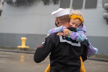 A Sailor, assigned to the Arleigh Burke-class guided-missile destroyer USS John S. McCain (DDG 56), hugs his daughter after arriving at Naval Station Everett, Washington, October 16, 2021.