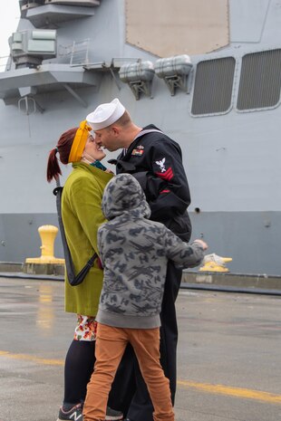 A Sailor, assigned to the Arleigh Burke-class guided-missile destroyer USS John S. McCain (DDG 56), gives his wife the first kiss after arriving at Naval Station Everett, Washington, October 16.