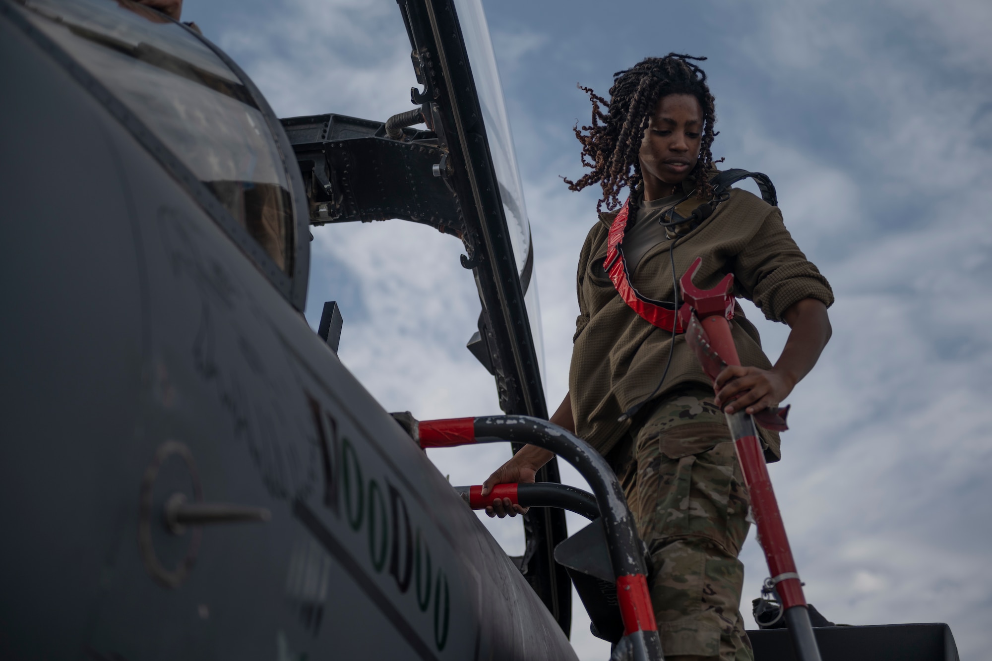 A crew chief stands on the ladder of an F-15E Strike Eagle