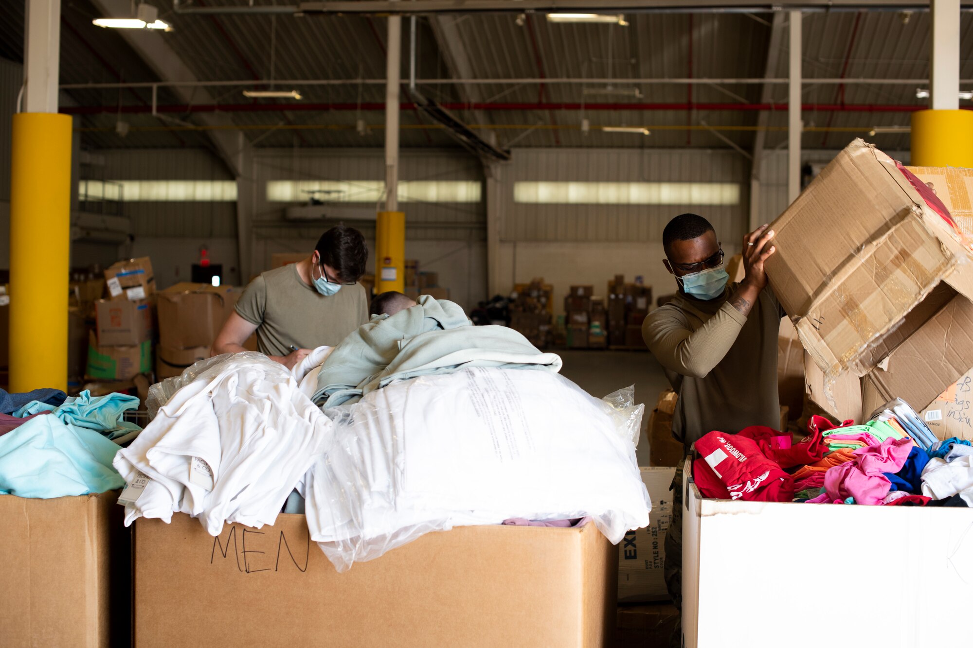 U.S. Air Force Senior Airman Thomas Sausto and Senior Airman Matthew Barabasz, members of Task Force Liberty, sort through donated cold weather clothing in Liberty Village, Joint Base McGuire-Dix-Lakehurst, New Jersey, Oct. 15, 2021. The Department of Defense, through U.S. Northern Command, and in support of the Department of Homeland Security, is providing transportation, temporary housing, medical screening, and general support for at least 50,000 Afghan evacuees at suitable facilities, in permanent or temporary structures, as quickly as possible. This initiative provides Afghan personnel essential support at secure locations outside Afghanistan. (U.S. Air Force photo by Tech. Sgt. Clayton Lenhardt)