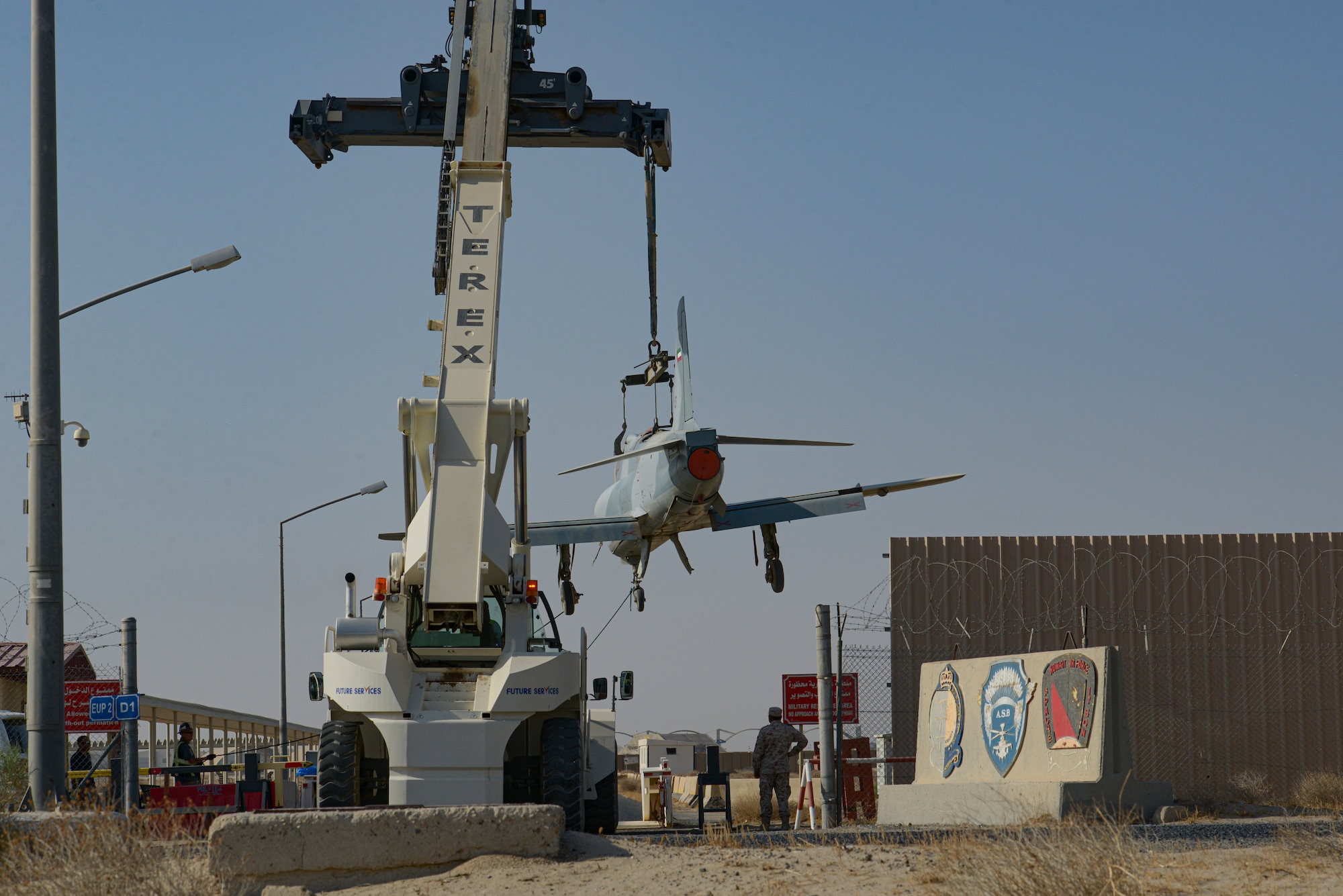 Multi-national forces lift a Kuwait Air Force Hawk aircraft over a gate on Ali Al Salem Air Base, Kuwait from Oct. 15, 2021.
