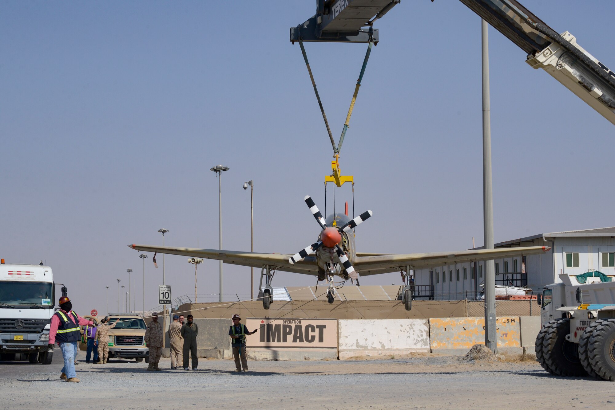 Multi-national forces lift a Kuwait Air Force Tucano aircraft over a gate on Ali Al Salem Air Base, Kuwait, from Oct. 15, 2021.
