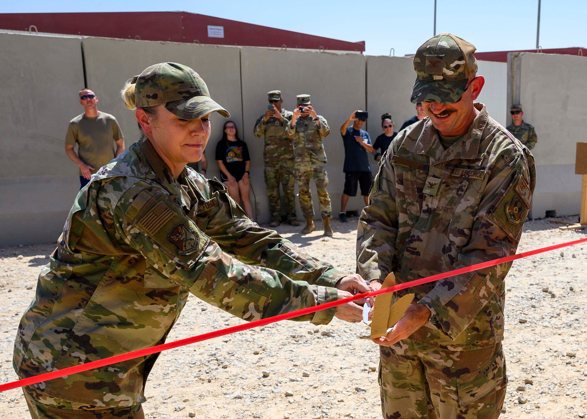 U.S. Air Force Col. Kevin Davidson, 378th Air Expeditionary Wing vice commander, and U.S Air Force Staff Sgt. Allison Fine, 378th Air Expeditionary Wing military justice noncommissioned officer-in-charge, cuts the ribbon symbolizing the opening of the U.S. Serve-Us Members Attic, Prince Sultan Air Base, Kingdom of Saudi Arabia, Sept. 11 2021. The attic acts as an organized donation center open around-the-clock for gently-used items and was started by an all-volunteer team led by Fine, modeled after the concept of an Airman’s Attic found on most Air Force bases. Joint members leaving PSAB are now able to donate unneeded items prior to departure while new members can acquire needed items for free, saving money and reducing the amount of waste produced at PSAB. (U.S. Air Force photo by Senior Airman Samuel Earick)