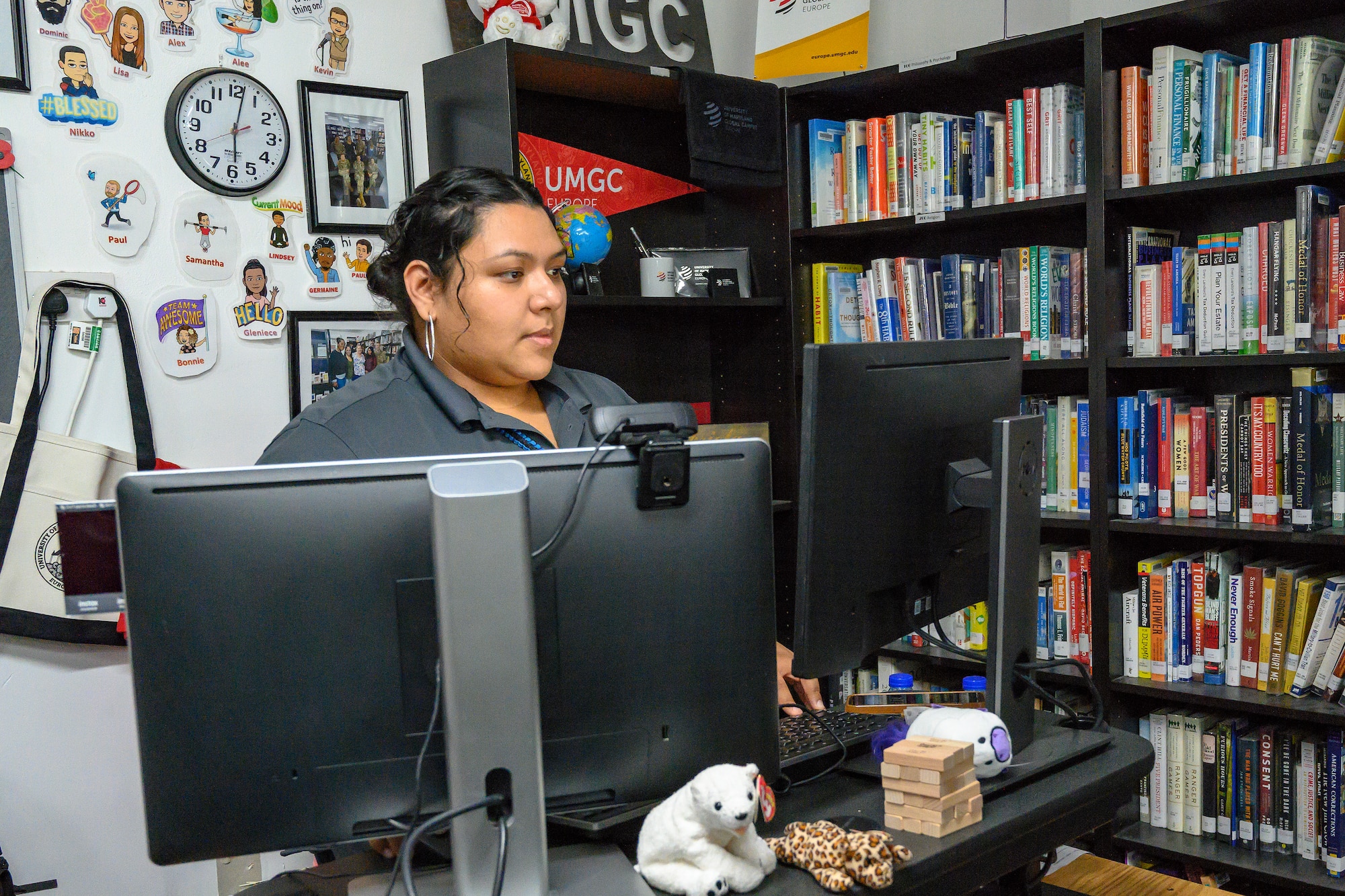 Civilian woman working on computer, surrounded by books