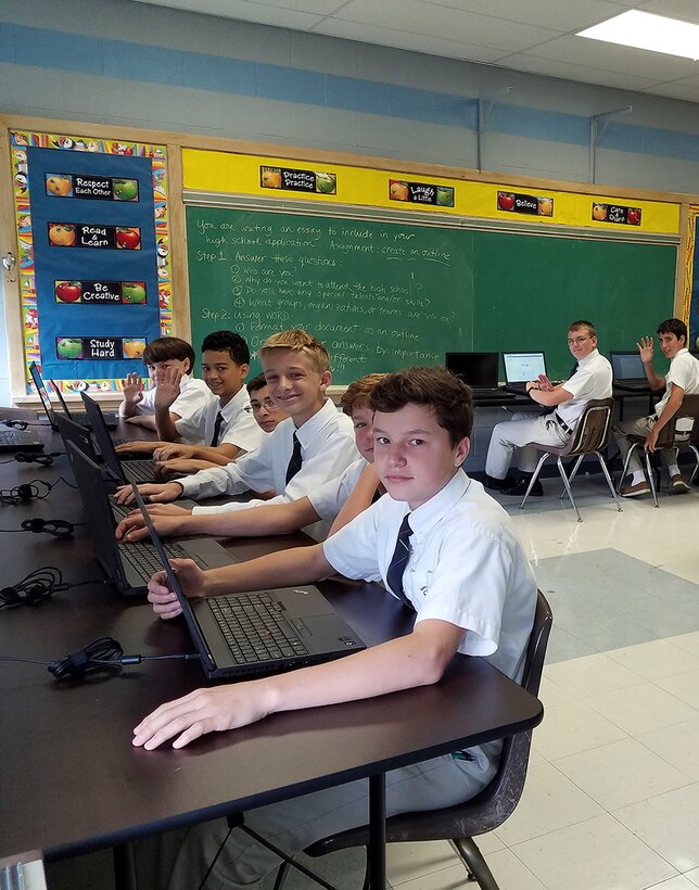 Young students sit in front of computers in a classroom.