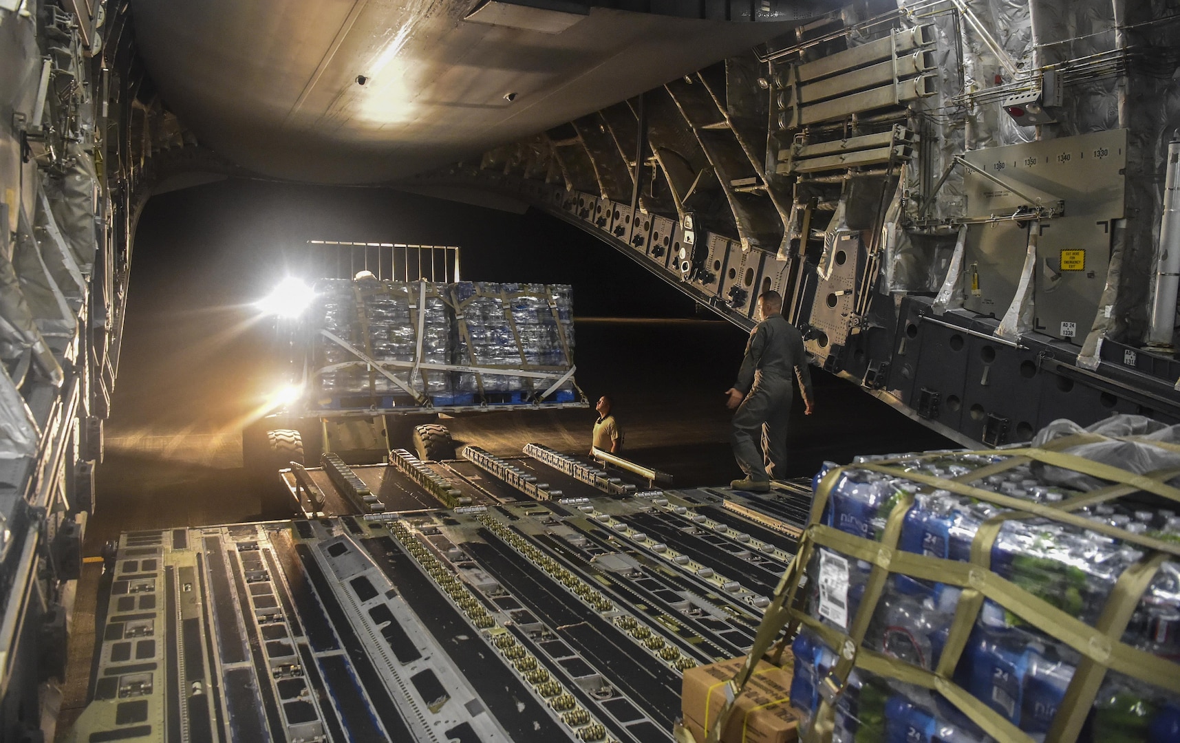 The inside of an aircraft with cases of water being loaded into the back.