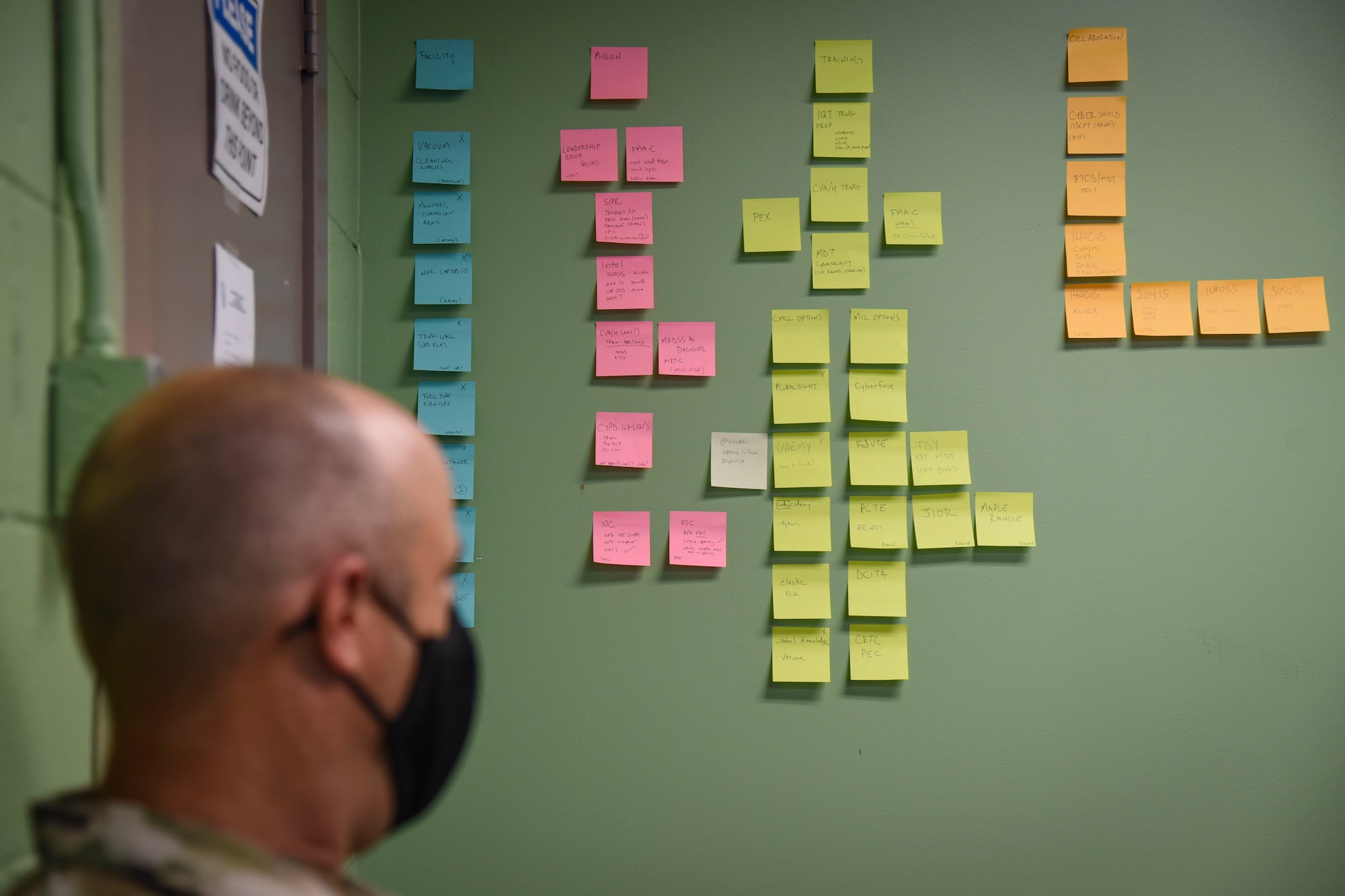 Master Sgt. Christopher Motta, non-commissioned officer-in-charge, 108th Communications Flight/ Mission Defense Team, looks at wall of Post-It notes stuck to the wall. The notes outline the process of standing up the new cyber mission as they become more acquainted with their new work area.