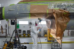 Airman 1st Class Dylan Varney sprays paint on to F-16