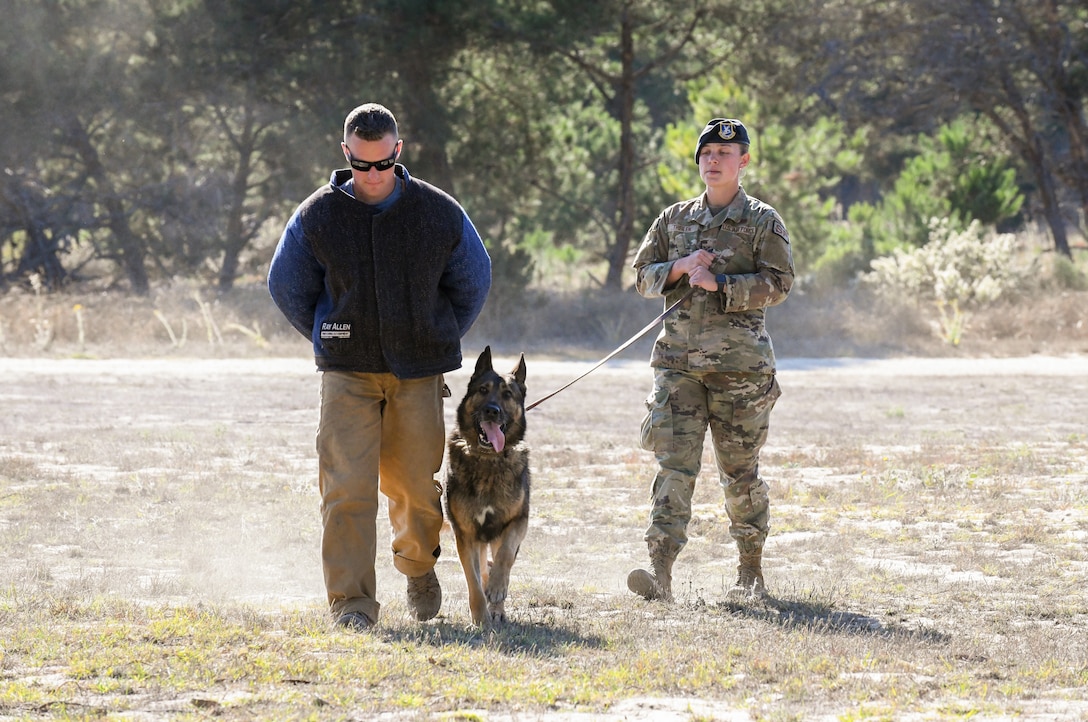 Staff Sgt. Ian Wilson, 30th Security Forces Squadron military working dog instructor, OSSY, 30th SFS military working dog, and Senior Airman Jenna Theilen, 30th SFS military working dog handler, demonstrate Ozzy’s ability to secure adversaries at the West Coast Warriors First Responders Appreciation Week on Oct. 15, 2021 at Vandenberg Space Force Base, Calif. (U.S. Space Force photo by Airman 1st Class Rocio Romo)