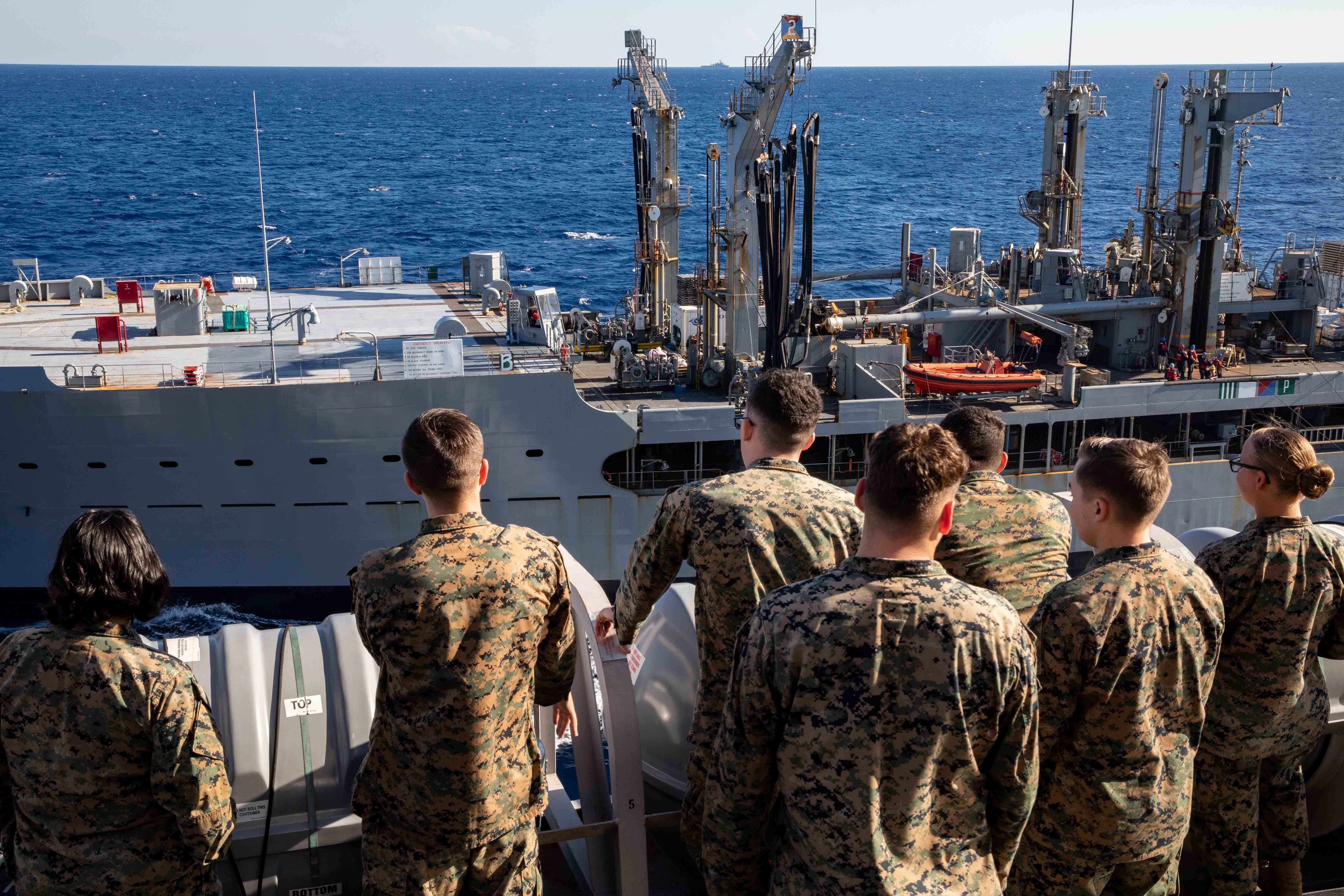 Marines watch from the starboard bridge wing of USS Arlington (LPD 24) as it pulls alongside USNS Leroy Grumman (T-AO 195) to conduct a replenishment-at-sea, Oct. 23, 2021.