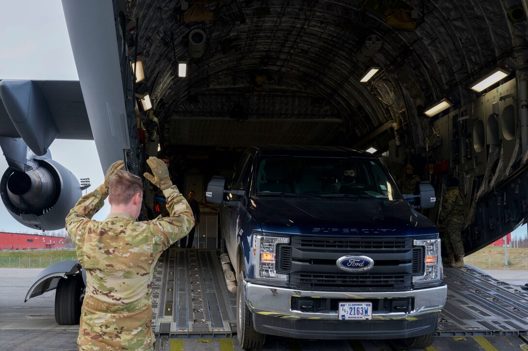 A 517th Airlift Squadron loadmaster guides Air Force Staff Sgt. Bryce Marquardt truck onto a C-17 Globemaster III during the Nodal Lightning at Ted Steven International Airport in Anchorage, Alaska on Oct. 19, 2021. The Nodal Lightning exercise allowed the 732nd AMS personnel to respond efficiently and effectively to contested or degraded contingency environments. Marquardt is assigned to the 732nd Air Mobility Squadron as an air terminal operations center supervisor.