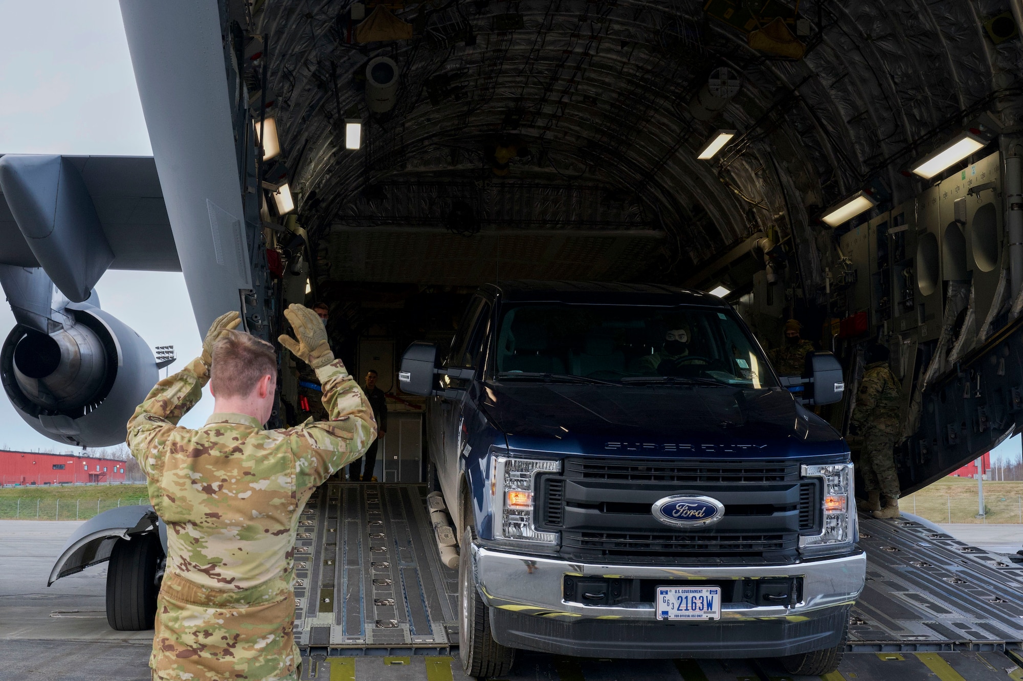 A 517th Airlift Squadron loadmaster guides Air Force Staff Sgt. Bryce Marquardt truck onto a C-17 Globemaster III during the Nodal Lightning at Ted Steven International Airport in Anchorage, Alaska on Oct. 19, 2021. The Nodal Lightning exercise allowed the 732nd AMS personnel to respond efficiently and effectively to contested or degraded contingency environments. Marquardt is assigned to the 732nd Air Mobility Squadron as an air terminal operations center supervisor.