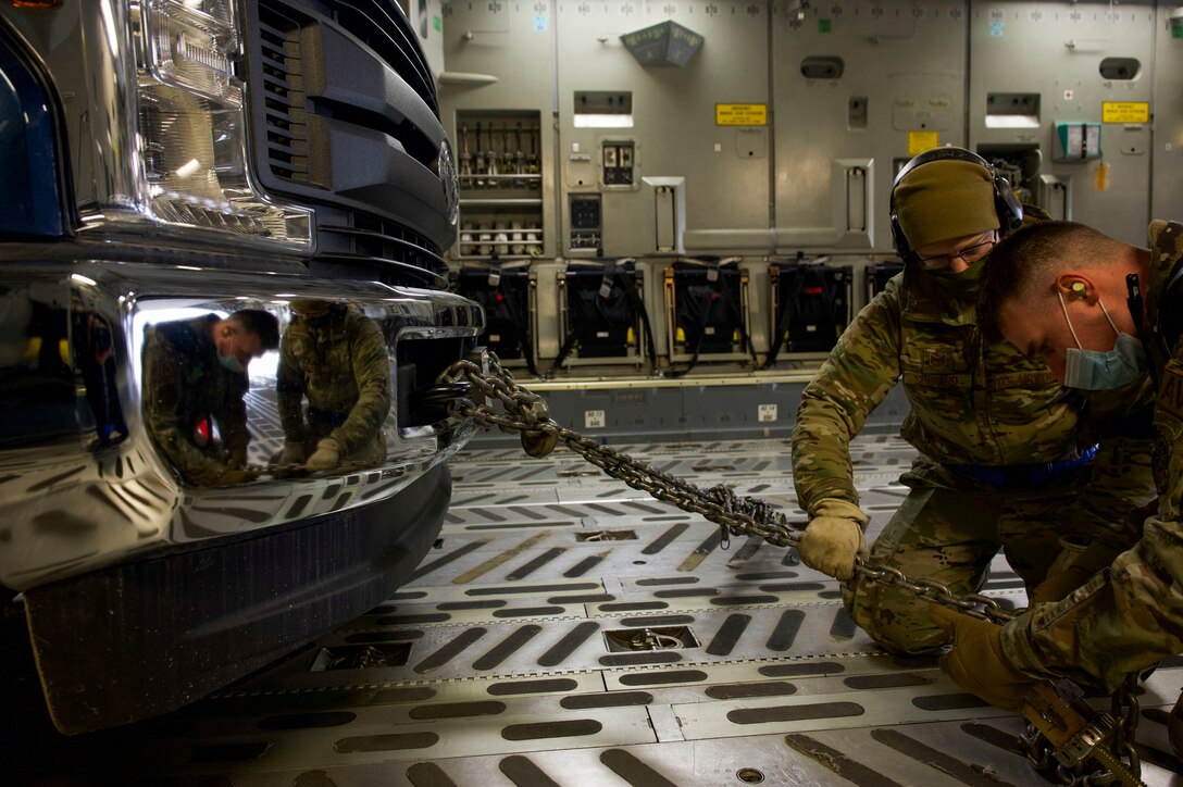 Air Force Staff Sgt. Josh Goodhart, foreground, and Tech. Sgt. Robert Shepard apply tie-down restraint after loading a truck onto a C-17 Globemaster III during the Nodal Lightning exercise at Ted Steven International Airport in Anchorage, Alaska, Oct. 19, 2021. The Nodal Lightning exercise allowed the 732nd AMS personnel to respond efficiently and effectively to contested or degraded contingency environments. Goodhart and Shepard are both assigned to the 732nd Air Mobility Squadron as an aircraft maintainer and air terminal operations center, respectively.