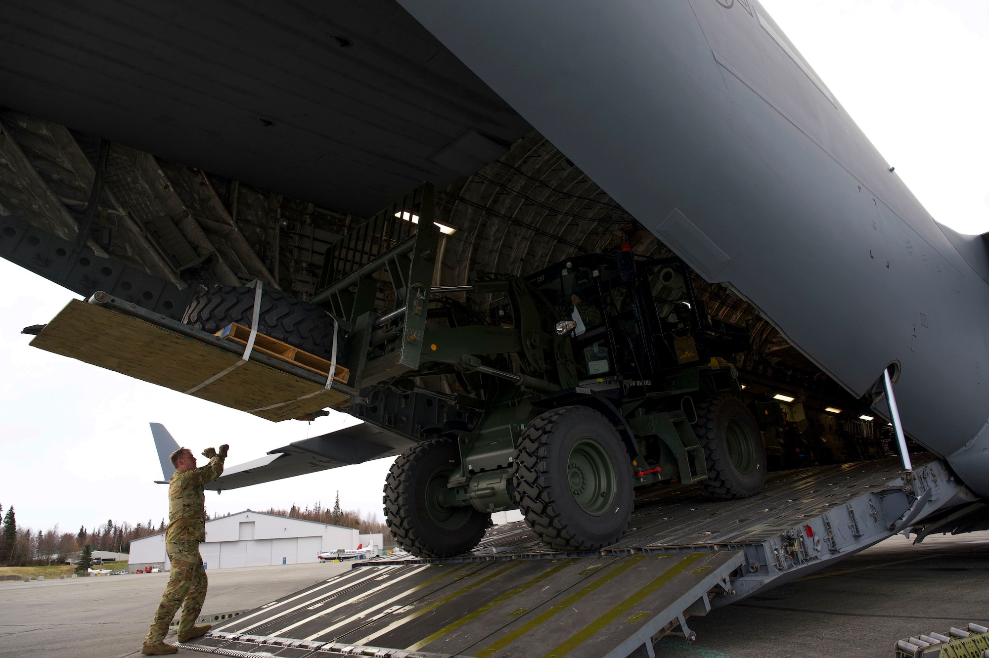 A loadmaster assigned to the 517th Airlift Squadron spots Senior Airman Jayme Williams, 732nd Air Mobility Squadron passenger service supervisor, as she downloads a 10K all-terrain forklift during the Nodal Lightning Exercise at Ted Stevens International Airport in Anchorage, Alaska, Oct. 19, 2021. The Nodal Lightning exercise allowed the 732nd AMS personnel to respond efficiently and effectively to contested or degraded contingency environments.