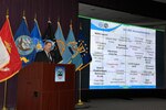 Sub-command director stands at a podium and speaks about topics included on a slide show presentation.