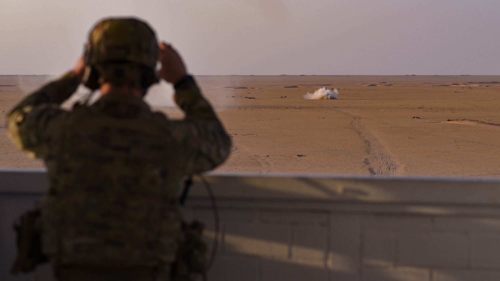 A U.S. Army 1st Battalion 194th Armor Regiment forward observer monitors an airstrike downrange at Udairi Range, Kuwait, Oct. 21, 2021. U.S. Air Force joint terminal attack controllers deployed to the 82nd Expeditionary Air Support Operations Squadron, along with the U.S. Army 1-194 AR joint fires observers in-training, and the Italian air force (Aeronautica Militare) Task Group Typhoon practiced close air support, fostered enduring partnerships and advanced its decisive combat dominance during a live-fire training exercise. (U.S. Air Force photo by Staff Sgt. Ryan Brooks)