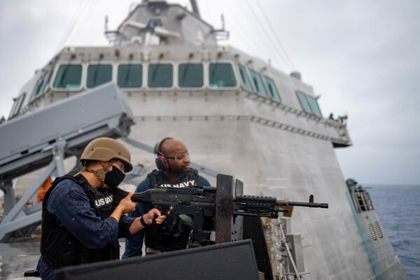Lt. Iman Amaya, from Orange Park, Fla., left, fires a M240D machine gun aboard Independence-variant littoral combat ship USS Charleston (LCS 18), during a live fire exercise.