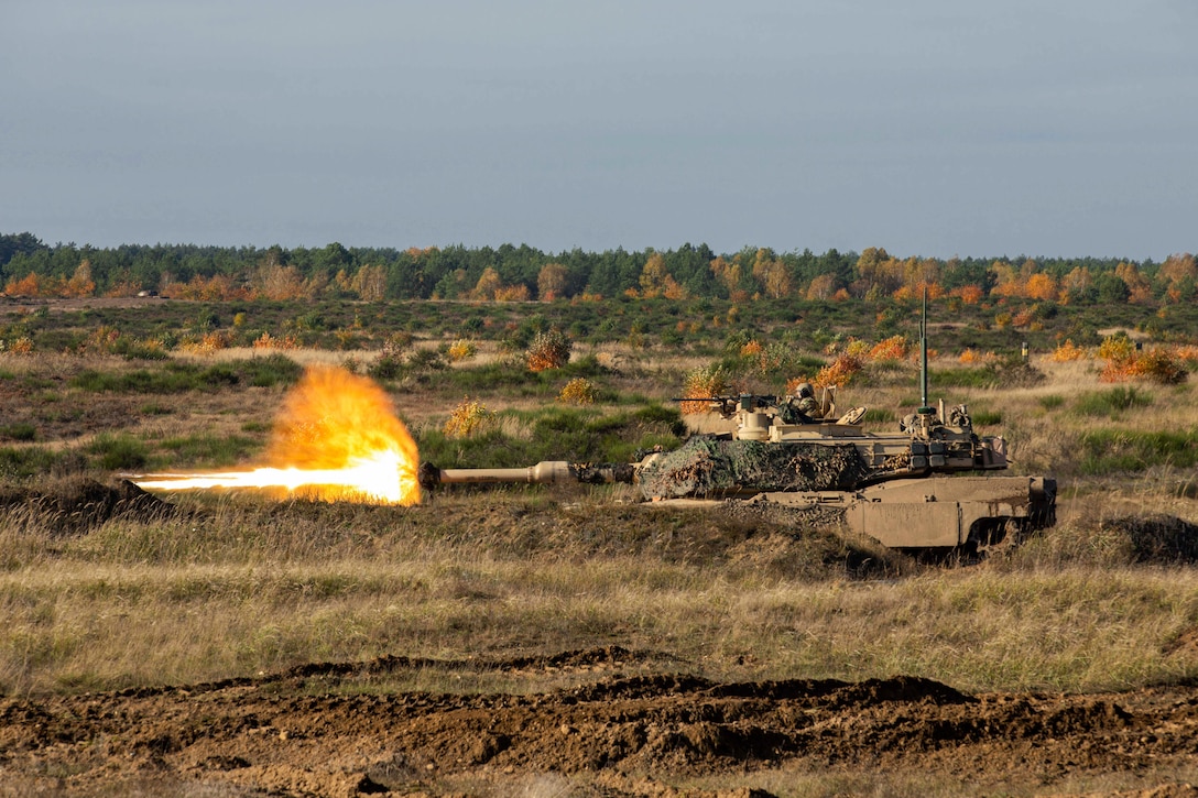 Soldiers fire a tank in a field.