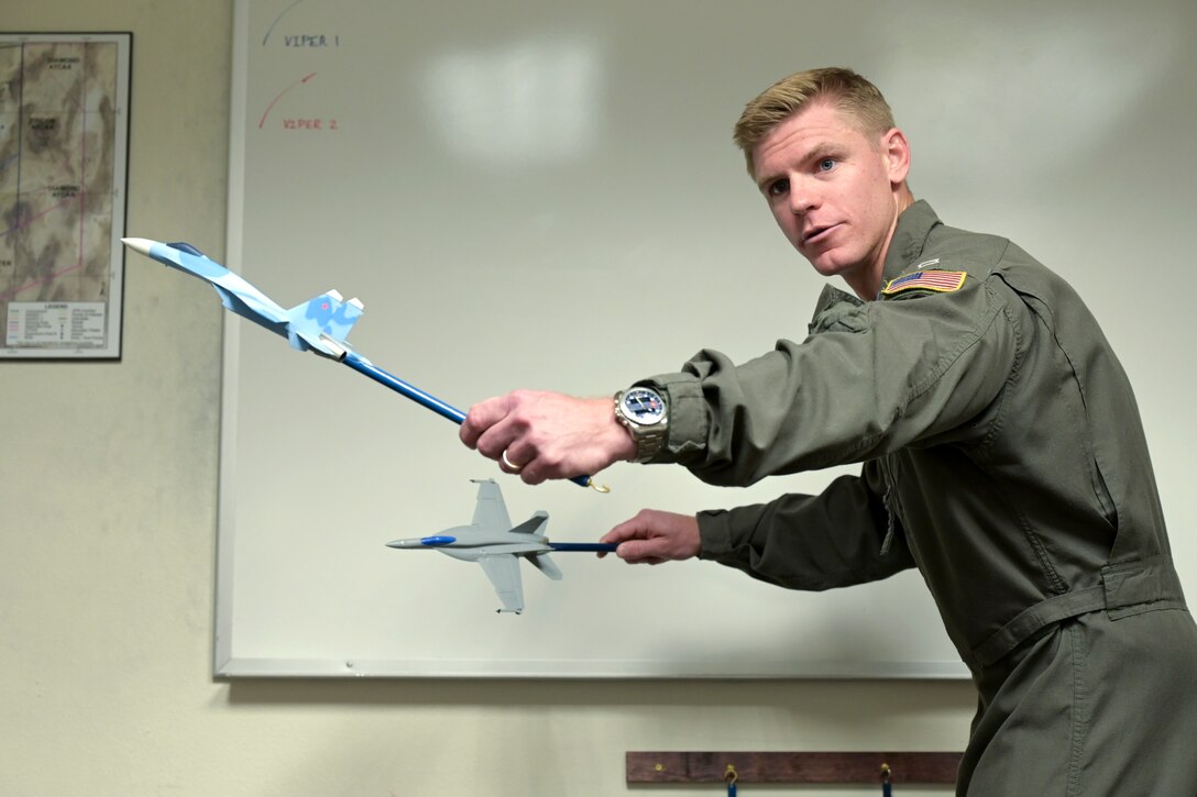 A man holds two sticks that have model fighter jets on the ends.