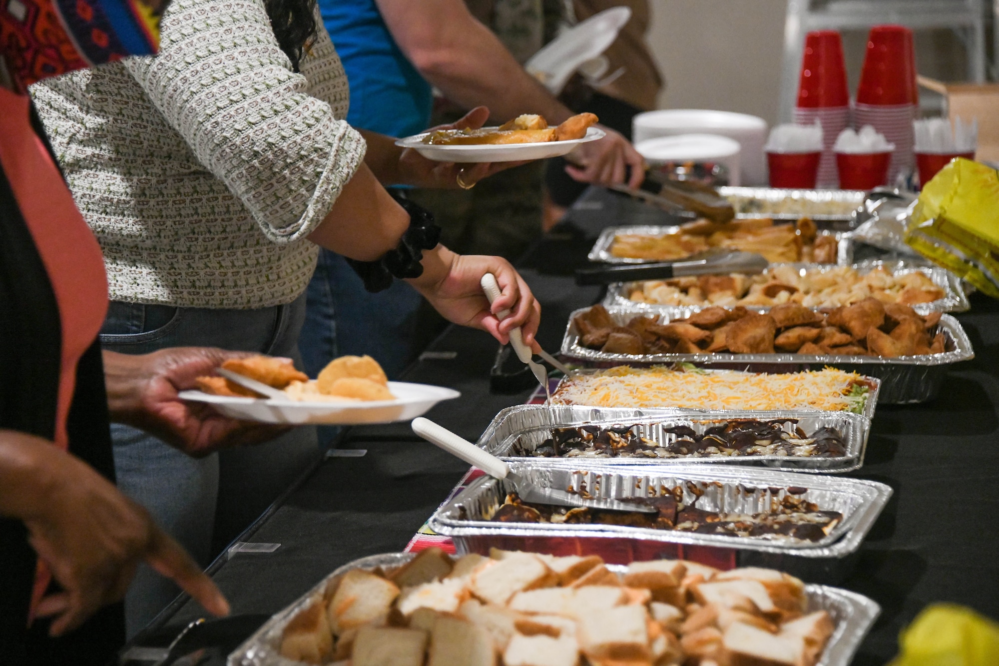 Airmen and families eat an assortment of traditional Hispanic dishes at a fiesta on Altus Air Force Base, Oklahoma, October 15, 2021. Guests were able to enjoy food cooked by several Airmen, which included empanadas, mole, and churros. (U.S. Air Force photo by Airman 1st Class Trenton Jancze)