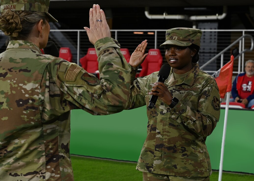 U.S. Air Force Col. Cat Logan, commander of Joint Base Anacostia-Bolling and the 11th Wing, leads Staff Sgt. Jaquisha Wright, assigned to the 11th Civil Engineer Squadron, through her first reenlistment ceremony during a D.C. United soccer game at Audi Field in Washington, D.C. on Oct. 16, 2021. The reenlistment ceremony served as a special military appreciation event during the game's halftime. (U.S. Air Force photo by Staff Sgt. Kayla White)