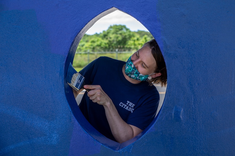 U.S. Marine Corps Capt. Mallory Owens, the Marine Corps Base (MCB) Camp Blaz adjutant, paints a bus stop located across from Naval Computer and Telecommunications Station (NCTS) Guam, Sept. 27, 2021.