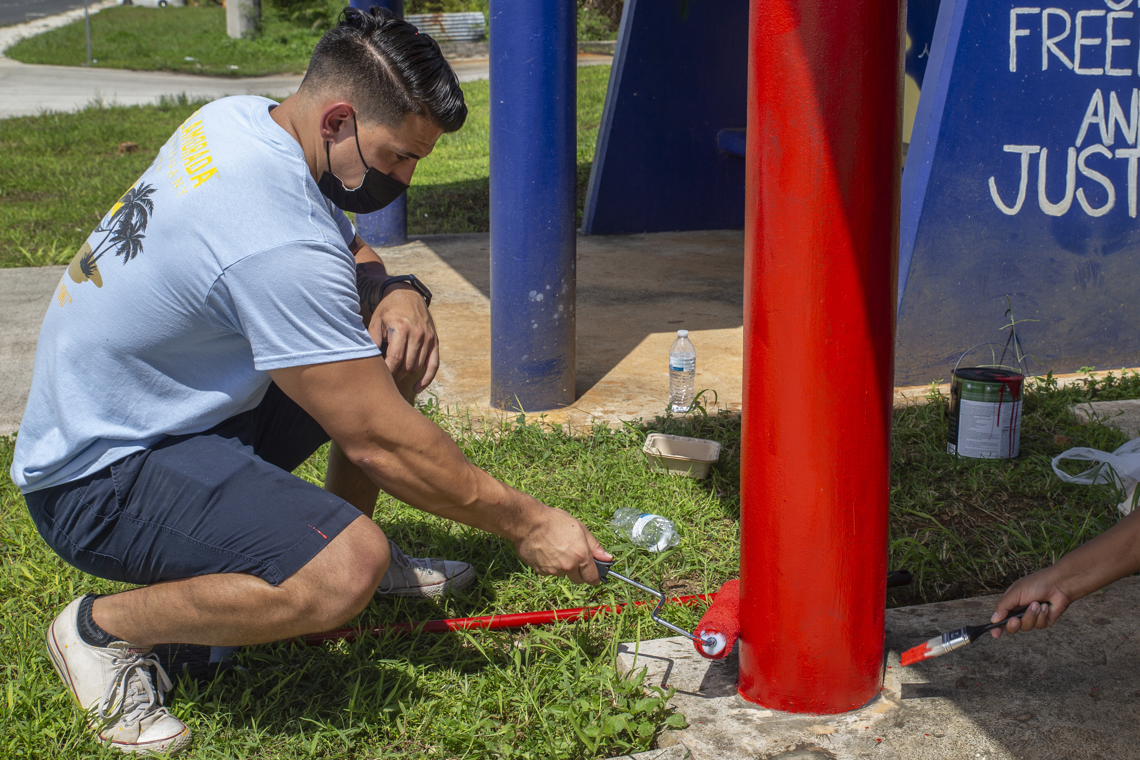 U.S. Marine Corps Capt. A.J. Ramos, the Marine Corps Base (MCB) Camp Blaz communication strategy and operations officer, paints a bus stop located across from Naval Computer and Telecommunications Station (NCTS) Guam, Sept. 27, 2021.