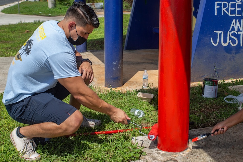 U.S. Marine Corps Capt. A.J. Ramos, the Marine Corps Base (MCB) Camp Blaz communication strategy and operations officer, paints a bus stop located across from Naval Computer and Telecommunications Station (NCTS) Guam, Sept. 27, 2021.