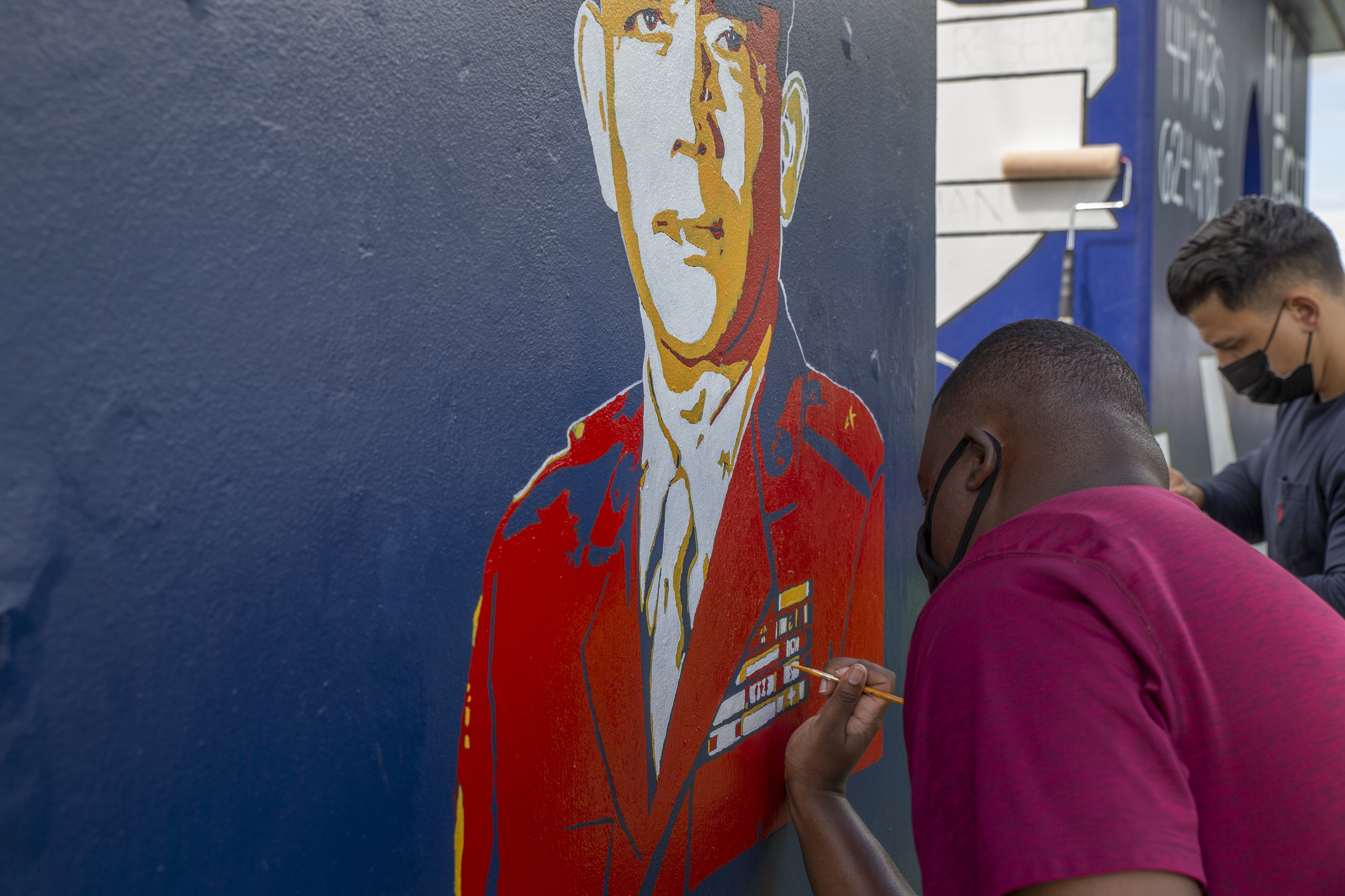 Stanley James, the Marine Corps Base (MCB) Camp Blaz communications strategy and operations deputy director, paints a bus stop located across from Naval Computer and Telecommunications Station (NCTS) Guam, Oct. 20, 2021.