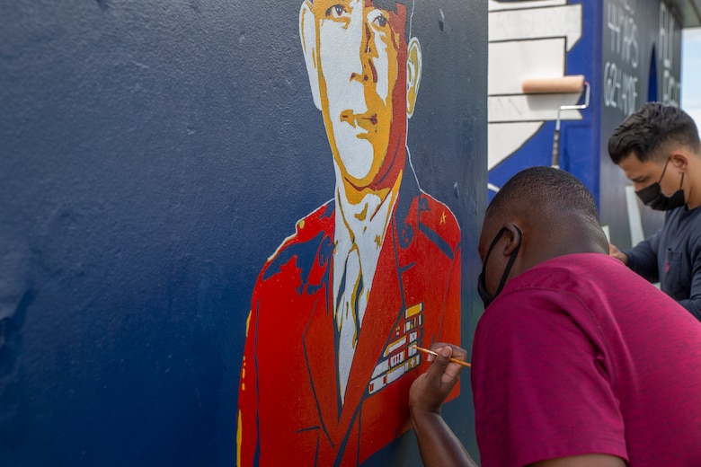 Stanley James, the Marine Corps Base (MCB) Camp Blaz communications strategy and operations deputy director, paints a bus stop located across from Naval Computer and Telecommunications Station (NCTS) Guam, Oct. 20, 2021.