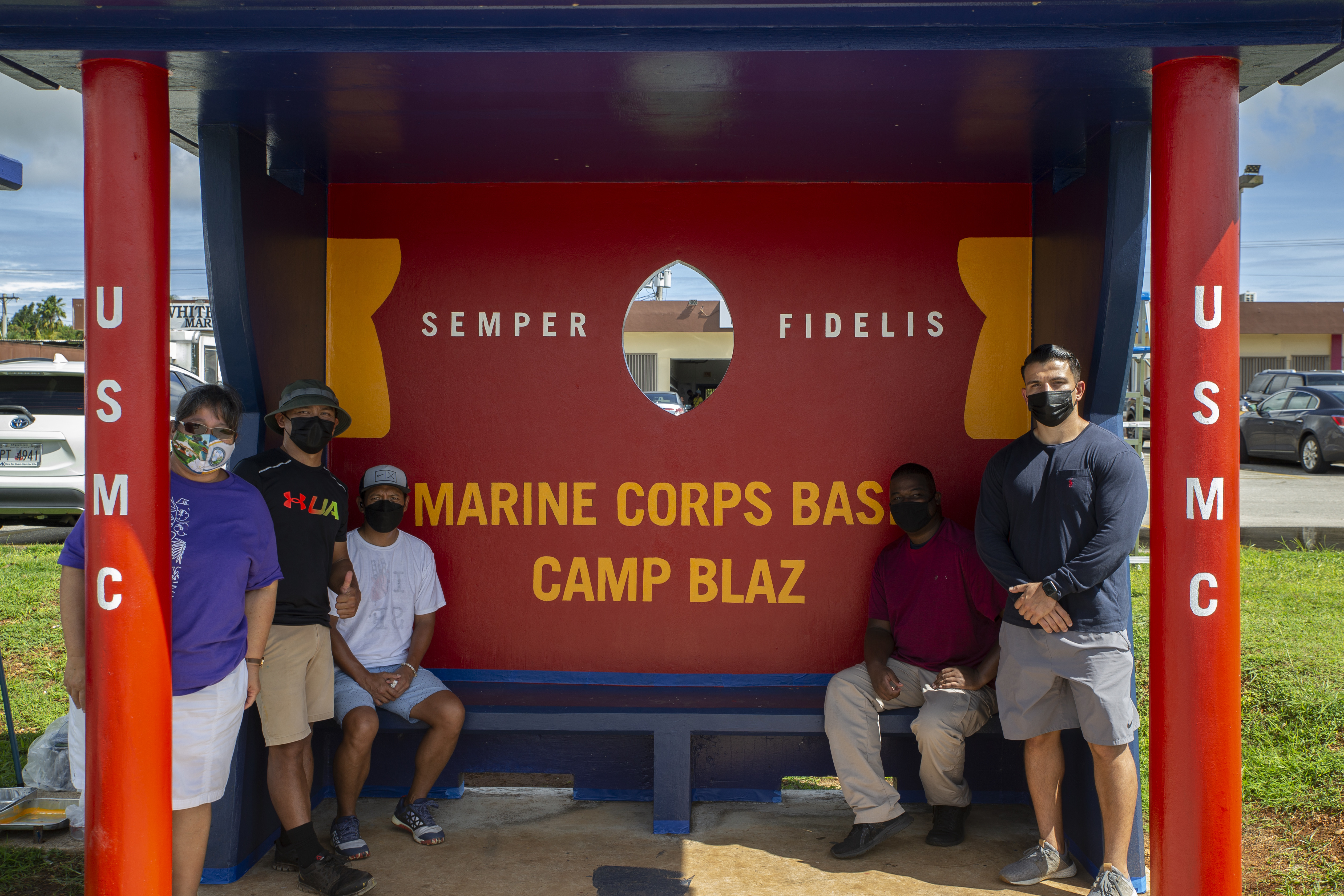 Volunteers with Marine Corps Base (MCB) Camp Blaz pose for a photograph at a bus stop with the mayor and vice mayor of Dededo, Guam, Oct. 20, 2021.