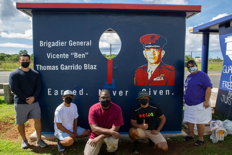 Volunteers with Marine Corps Base (MCB) Camp Blaz pose for a photograph at a bus stop with the mayor and vice mayor of Dededo, Guam, Oct. 20, 2021.