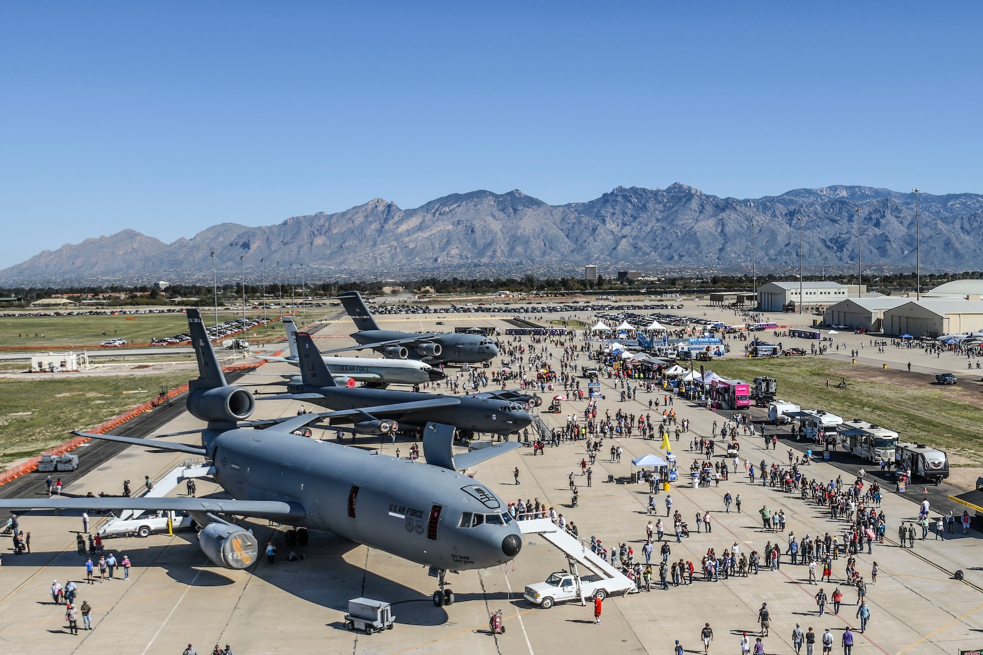 aircraft are displayed on the flight line during an air show surrounded by attendees.