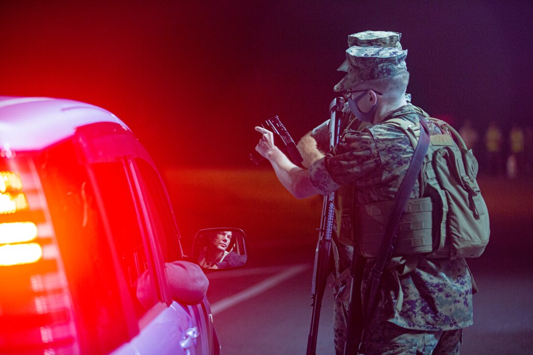 U.S. Marines with Security Guard Force, Camp Courtney, inspect an oncoming vehicle during Operation Constant Vigilance on Camp Courtney, Okinawa, Japan, Oct. 19, 2021. After a visual confirmation of a simulated vehicle-borne improvised explosive device, SGF and Explosive Ordnance Disposal, with Marine Corps Base Camp Butler, conducted response measures to include detainee handling, EOD robotics techniques, and vehicle inspection procedures. Constant Vigilance is an island-wide force protection condition evaluation and crisis response to validate regional, installation, camp, and tenant antiterrorism and mission assurance plans and policies. (U.S. Marine Corps photo by Lance Cpl. Alex Fairchild)