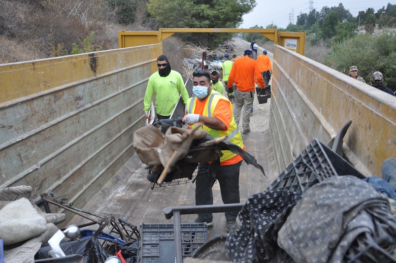 A steady stream of contracted workers fills one of 82 dumpsters used during the San Gabriel River and San Jose Creek cleanup. A total of 575 tons of debris were removed during the two-week project. The U.S. Army Corps of Engineers Los Angeles District cleared about 120 acres of riverbank, Sept. 27-Oct. 22, 2021.