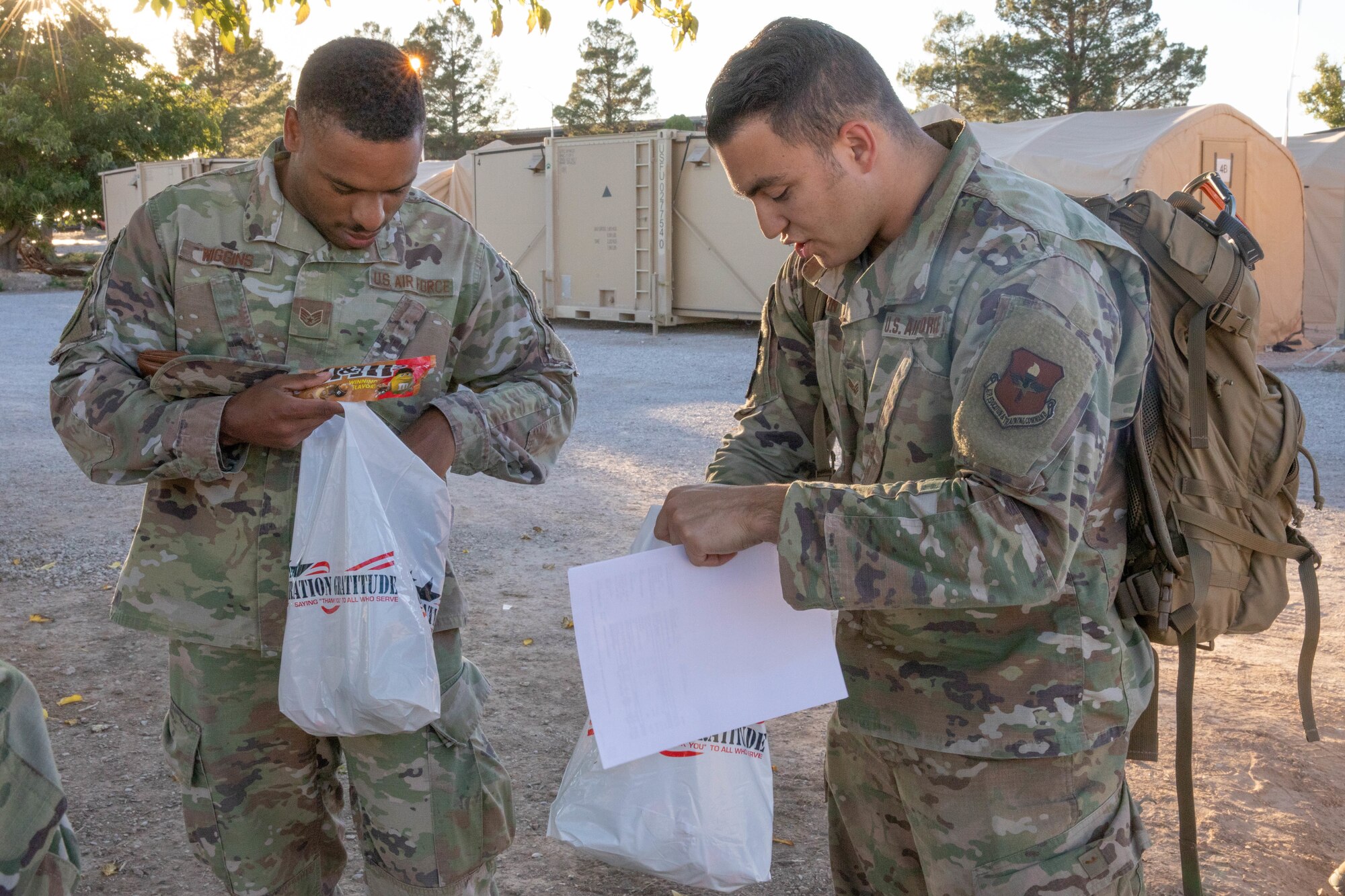 U.S. Air Force Staff Sgt. Lonzo Wiggins and Senior Airman Steven Borin, both assigned to Task Force Holloman, receive care packages from Operation Gratitude, as a thanks for their hard work on Holloman Air Force Base, New Mexico, Oct. 19, 2021. The Department of Defense, through U.S. Northern Command, and in support of the Department of Homeland Security, is providing transportation, temporary housing, medical screening, and general support for at least 50,000 Afghan evacuees at suitable facilities, in permanent or temporary structures, as quickly as possible. This initiative provides Afghan personnel essential support at secure locations outside Afghanistan. (U.S. Army Photo By Pfc. Anthony Ford)