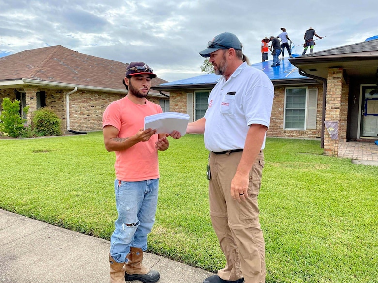 Kansas City District, U.S. Army Corps of Engineers National Local Government Liaison and Engineering Technician Derek Wansing (right) shares Operation Blue Roof flyers with contracting lead Ramon Nieto in support of the Hurricane Ida disaster relief mission in Louisiana on Sept. 28, 2021.
