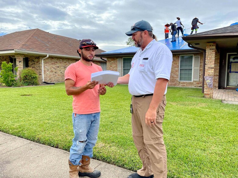 Kansas City District, U.S. Army Corps of Engineers National Local Government Liaison and Engineering Technician Derek Wansing (right) shares Operation Blue Roof flyers with contracting lead Ramon Nieto in support of the Hurricane Ida disaster relief mission in Louisiana on Sept. 28, 2021.