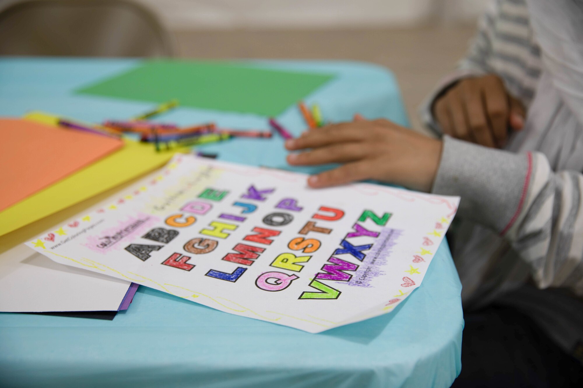 An Afghan child colors in the letters of the English alphabet during the opening of a new education center at Aman Omid Village on Holloman Air Force Base, New Mexico, Oct. 19, 2021. The Department of Defense, through U.S. Northern Command, and in support of the Department of Homeland Security, is providing transportation, temporary housing, medical screening, and general support for at least 50,000 Afghan evacuees at suitable facilities, in permanent or temporary structures, as quickly as possible. This initiative provides Afghan personnel essential support at secure locations outside Afghanistan. (U.S. Army Photo By Pfc. Anthony Ford)