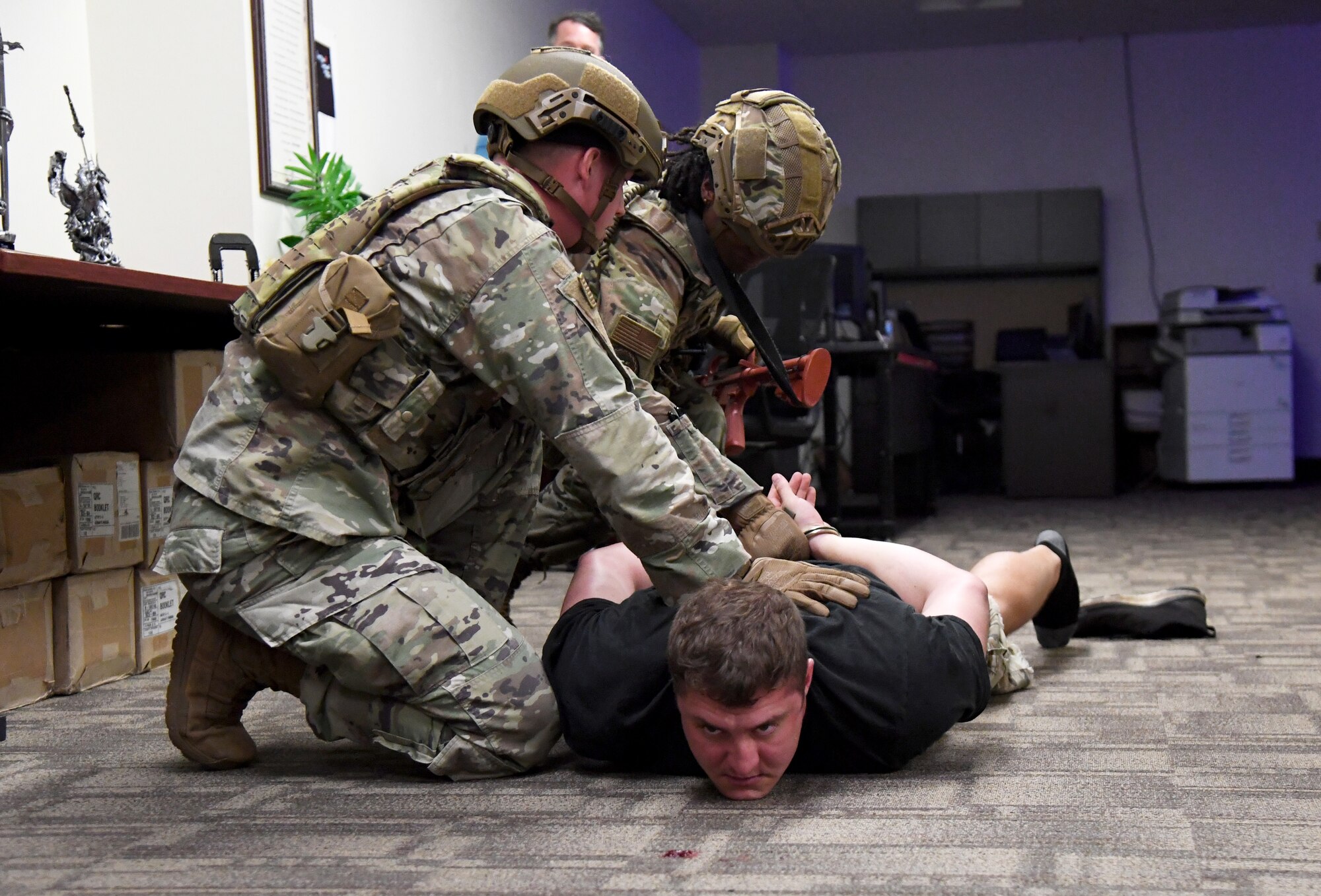 U.S. Air Force Staff Sgt. Bradley Hall, 81st Security Forces Squadron patrolman, and Senior Airman Breanna Thomas, 81st SFS patrolman, detain Staff Sgt. Matthew Storer, 81st Training Support Squadron force development NCO in charge portraying an active shooter, during an active shooter exercise inside the Taylor Logistics Center at Keesler Air Force Base, Mississippi, Oct. 21, 2021. The scenario included an active duty Air Force member who simulated open fire in order to test the base's ability to respond to and recover from a mass casualty event. (U.S. Air Force photo by Kemberly Groue)
