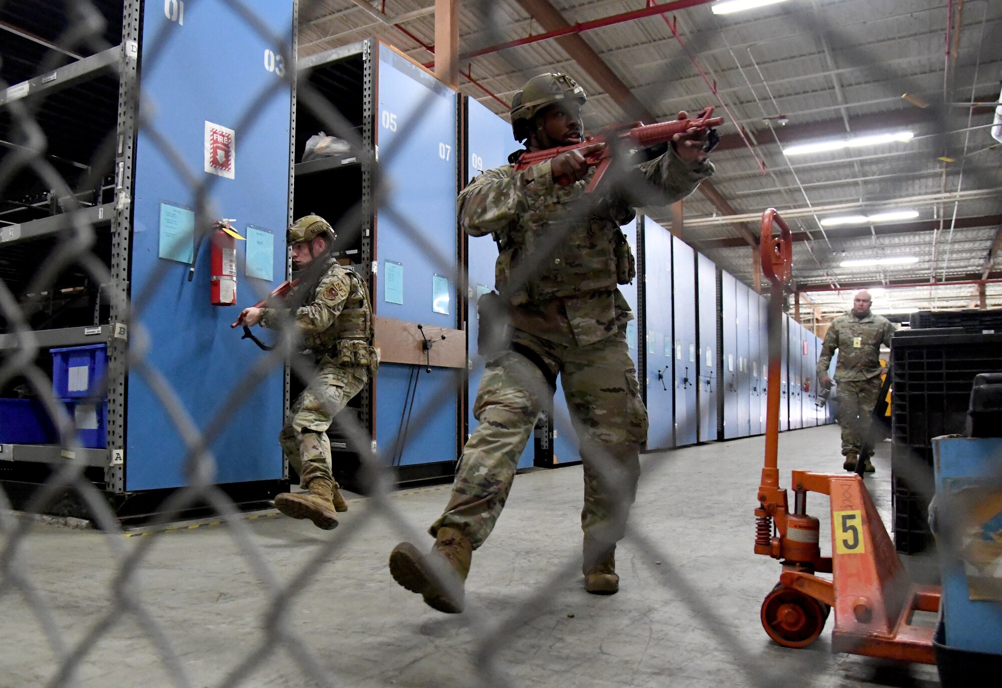 U.S. Air Force Airman 1st Class John Roach, 81st Security Forces Squadron entry controller, and Tech. Sgt. James Wilson, 81st SFS installation security NCO in charge, conduct a sweep inside the Taylor Logistics Center during an active shooter exercise at Keesler Air Force Base, Mississippi, Oct. 21, 2021. The scenario included an active duty Air Force member who simulated open fire in order to test the base's ability to respond to and recover from a mass casualty event. (U.S. Air Force photo by Kemberly Groue)