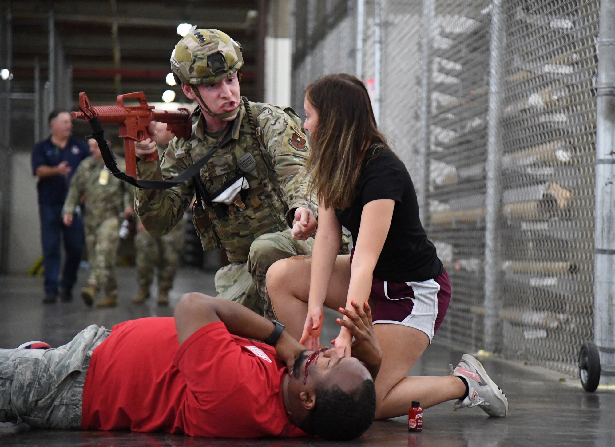 U.S. Air Force Airman 1st Class John Roach, 81st Security Forces Squadron entry controller, checks the medical status of "victims", Tech. Sgt. Mario Hartaway, 81st Healthcare Operations Squadron pediatrics flight chief, and Airman 1st Class Makenzie Vinson, 336th Training Squadron student, during an active shooter exercise inside the Taylor Logistics Center at Keesler Air Force Base, Mississippi, Oct. 21, 2021. The scenario included an active duty Air Force member who simulated open fire in order to test the base's ability to respond to and recover from a mass casualty event. (U.S. Air Force photo by Kemberly Groue)
