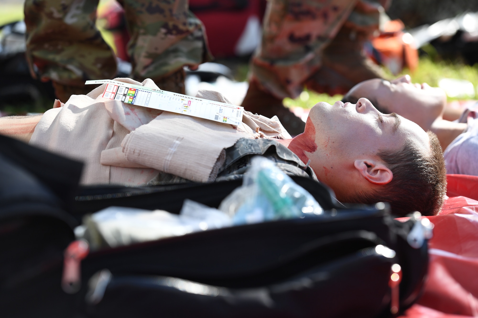 Airmen portraying victims receive medical assistance in the triage area during an active shooter exercise outside the Taylor Logistics Center at Keesler Air Force Base, Mississippi, Oct. 21, 2021. The scenario included an active duty Air Force member who simulated open fire in order to test the base's ability to respond to and recover from a mass casualty event. (U.S. Air Force photo by Kemberly Groue)