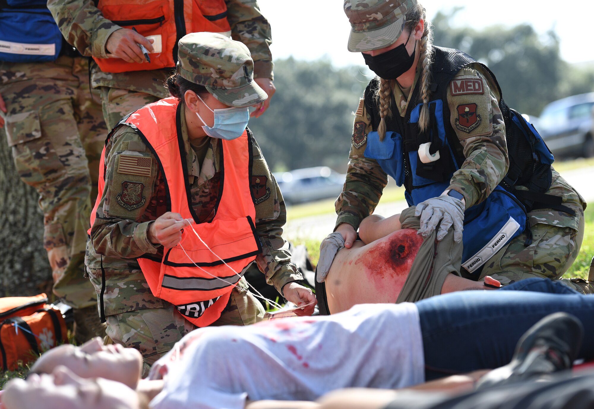 U.S. Air Force 1st Lt. Lucia Moreno, 81st Operational Medical Readiness Squadron medical flight nurse, and Airman Kaylee Exum, 81st OMRS medical technician, provides medical assistance to a "victim" during an active shooter exercise outside the Taylor Logistics Center at Keesler Air Force Base, Mississippi, Oct. 21, 2021. The scenario included an active duty Air Force member who simulated open fire in order to test the base's ability to respond to and recover from a mass casualty event. (U.S. Air Force photo by Kemberly Groue)
