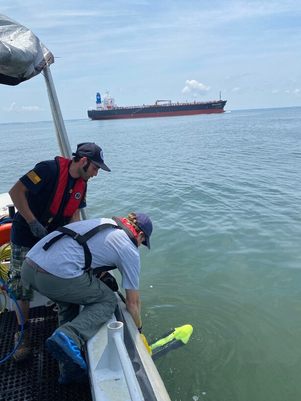 Dr. George Schwarz and Agustin Ortiz deploy the side scan sonar from NHHC research vessel.