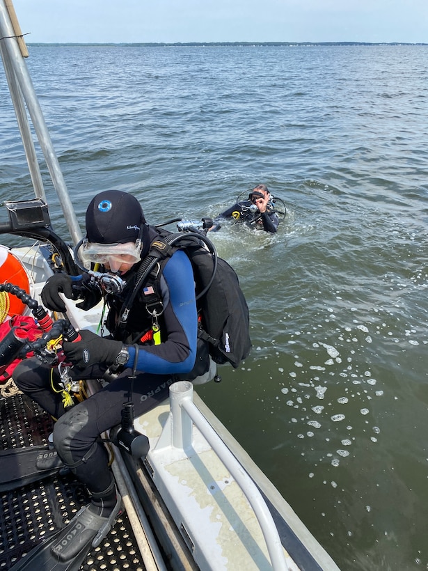 George Schwarz prepares to enter the water with video equipment while NHHC Reservist diver Joe Harvey gives an okay signal to topside.